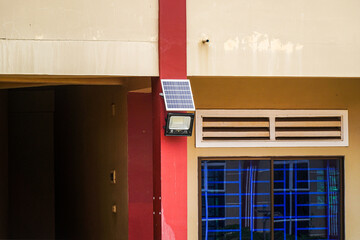 Architectural detail featuring a solar panel-powered light fixture mounted on a building's facade,...
