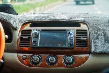 Interior car dashboard showcasing modern entertainment and climate control, emphasizing comfort and technology for a smooth driving experience. Wood trim adds a touch of elegance.