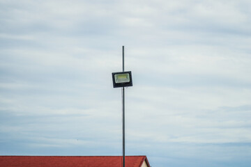 A versatile shot showing a modern outdoor LED light fixture mounted on a pole against a bright,...