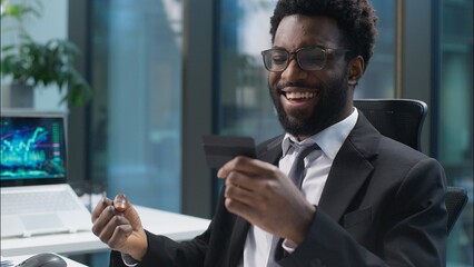 Happy joyful African American man holding banking credit card online buying consumer payment...