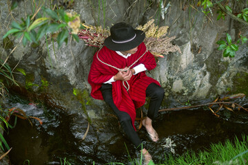 Andean man wearing traditional clothes refreshing in a stream