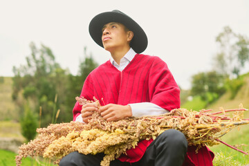 Young latin american farmer wearing a traditional poncho sits in a cultivated field