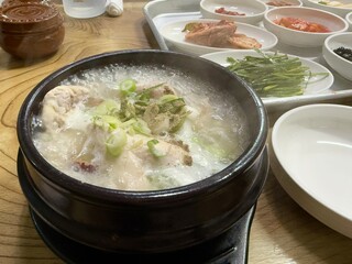 Samgyetang served hot in ttukbaegi or the black hot pot with various side dish on the table in a restaurant