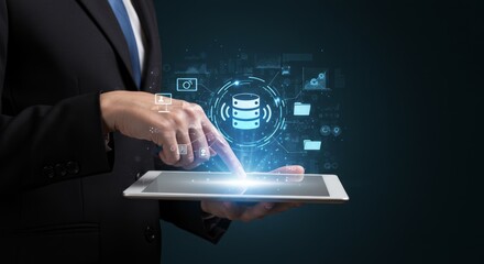A person in a suit uses a tablet, interacting with an illuminated data storage icon with surrounding digital elements