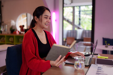 Asian female freelancer working productively at modern vibrant coworking space adult woman typing...