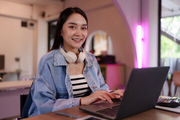 Asian young adult woman freelancer working remote on laptop for business productivity at modern...