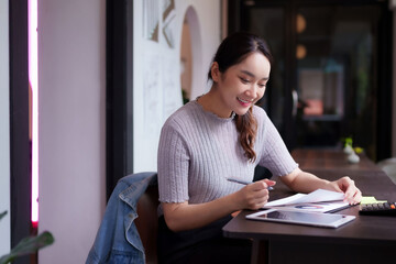 Asian adult woman freelancer digital nomad deep work reviewing business documents charts reports...