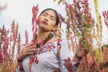 Young indigenous woman farmer with closed eyes, wearing traditional embroidered clothing and a...