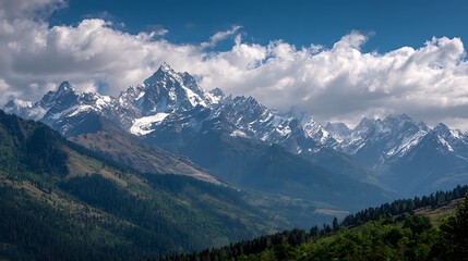 Fototapeta premium SnowCapped Mountain Range Under Blue Sky with Clouds, Lush Green Forest Slopes
