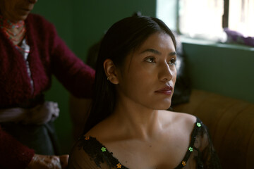 Indigenous woman getting ready with family member braiding her hair