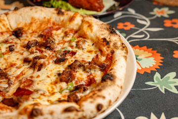 Delicious Italian Pizza with Toppings and Melted Cheese on a Floral Tablecloth