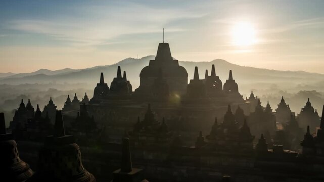 Sunrise over Borobudur Temple - The ancient Borobudur Temple in Indonesia is silhouetted against a misty sunrise.