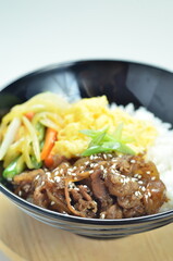 Yakiniku, grilled beef meats topped on a bowl of rice with vegetables, in the local restaurant...