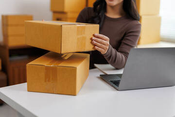 Online seller arranging cardboard boxes for delivery using laptop
