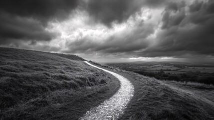 Winding Stone Path on Grassy Hill Under Dramatic Cloudy Sky, Black and White