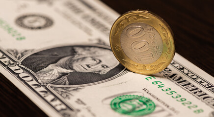 A 100 Kazakhstani tenge coin against a 1 US dollar bill