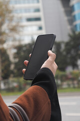 Holding a smartphone in an urban setting during the day