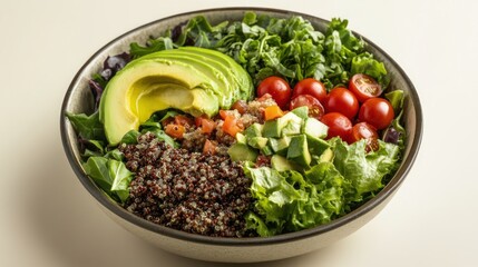 A vibrant quinoa salad bowl features sliced avocado, cherry tomatoes, cucumber, and mixed greens in a dark-grey bowl on a light beige background