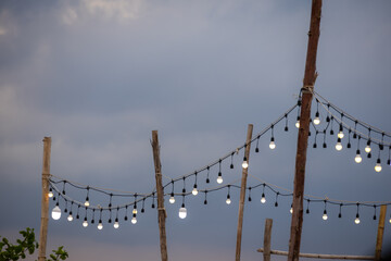 outdoor string lights hanging between rustic wooden posts against a twilight sky. The warm glow of...