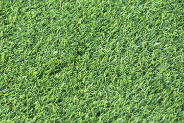 close-up of a lush, green artificial turf. The synthetic blades of grass are perfectly aligned and...