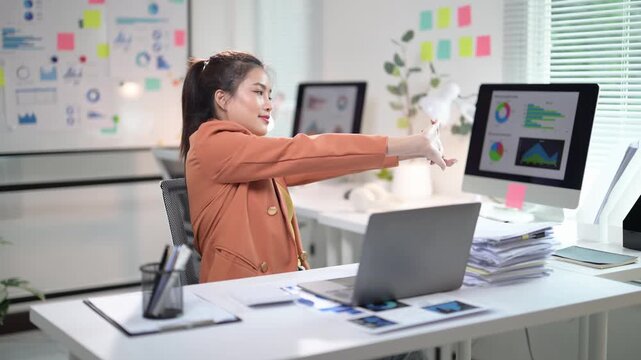 Asian accountant woman stretching her arms at work