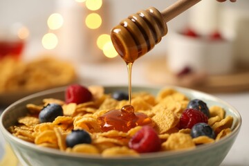 Honey drizzling onto cereal with berries breakfast