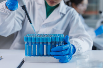 Scientist analyzing test tubes with micropipette in laboratory