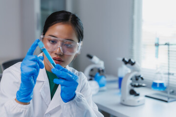 Scientist analyzing test tube with blue liquid in laboratory