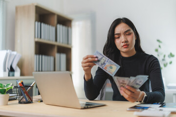 Businesswoman counting american dollars at office desk