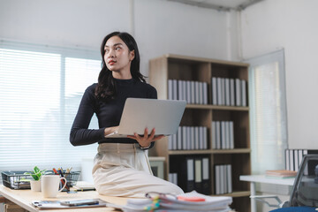 Businesswoman holding laptop and thinking in modern office