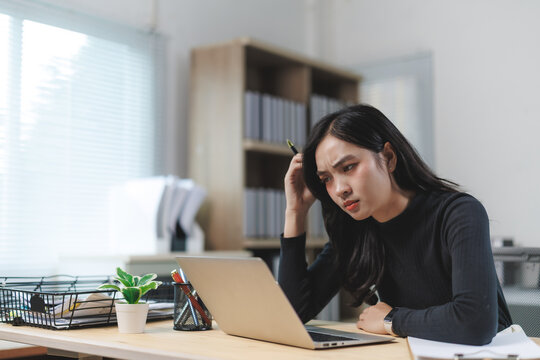 Stressed asian businesswoman having problems using laptop at office desk