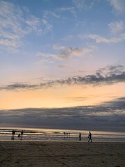 Fototapeta premium Dramatic Sunset Over Calm Sea with People Enjoying the Shoreline
