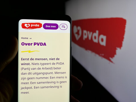 Stuttgart, Germany - 07-10-2025: Person holding smartphone with web page of Partij van de Arbeid van Belgie (PVDA) on screen in front of logo. Focus on center of phone display.