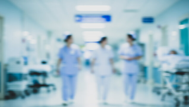Three healthcare workers walk in a blurred hospital corridor with medical equipment.premium photo of a blurry hospital room for posters, banners, and pamphlets