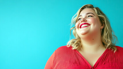 Fototapeta premium Confident plus-size woman with curly hair, standing with crossed arms and beaming smile against vibrant turquoise backdrop