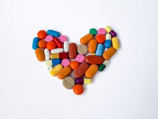 Colorful Pills and Capsules Forming Heart Shape on White Background