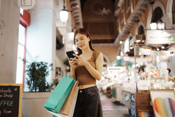 Young woman enjoying night shopping outdoors, holding bags and smiling happily, surrounded by city lights and a vibrant, modern retail atmosphere.