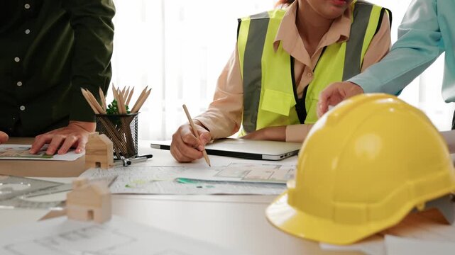 Professional engineer measuring the blueprint. Professional engineer working architectural project at studio on a table with yellow helmet and architectural equipment scatter around. Delineation.
