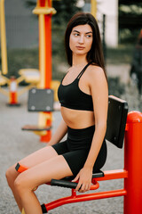 Young woman exercising outdoors at a fitness park in summer