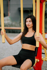 Young woman exercising on outdoor gym equipment in a public park during daylight