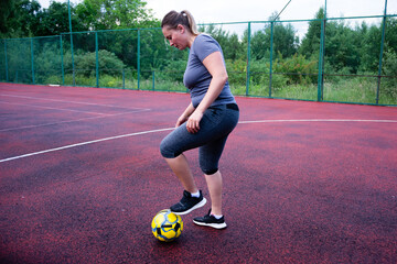 Woman practicing soccer skills on a red court. Focused and determined, she controls the ball.