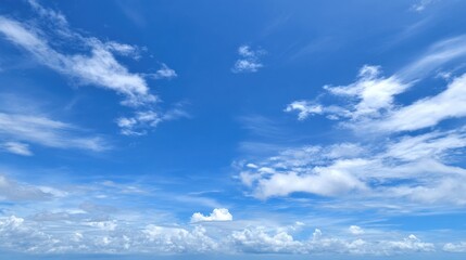 Vivid blue sky stretches above, dotted with fluffy white clouds. The clear weather reflects sunlight beautifully, creating a serene atmosphere in a coastal area.