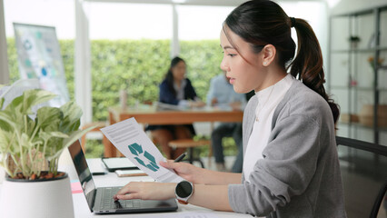 The way forward save the planet earth Gen Z female asia people go green net zero waste control ESG audit office desk. Young adult woman asian SDG carbon credit tax auditor busy happy work using laptop
