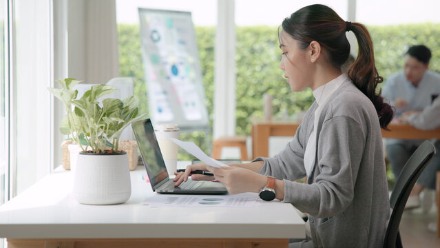 The way forward save the planet earth Gen Z female asia people go green net zero waste control ESG audit office desk. Young adult woman asian SDG carbon credit tax auditor busy happy work using laptop