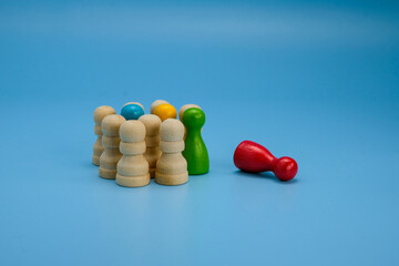 A group of wooden pawns, with one red pawn isolated on the side, symbolizing exclusion,...
