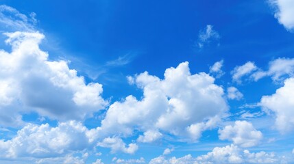 Fototapeta premium Bright blue sky hosts fluffy white clouds gliding gently during midday. The tranquil atmosphere invites relaxation and reflection on a beautiful day.