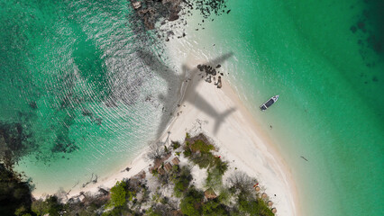 Aerial view of shadow passenger plane silhouette and sandy beach blue sea with waves at sea beach summer vacation sea travel concept	
