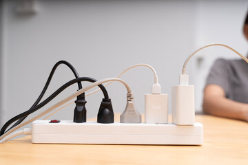 Power strip with multiple plugs and cables connected on wooden table, electricity and energy supply concept