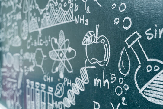 Science chalkboard with hand-drawn chemistry formulas, physics equations, DNA, and educational doodles in classroom