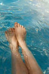 A girl's feet in a blue pool. Epilation of legs, varicose veins. Rest, relaxation on the beach, at...